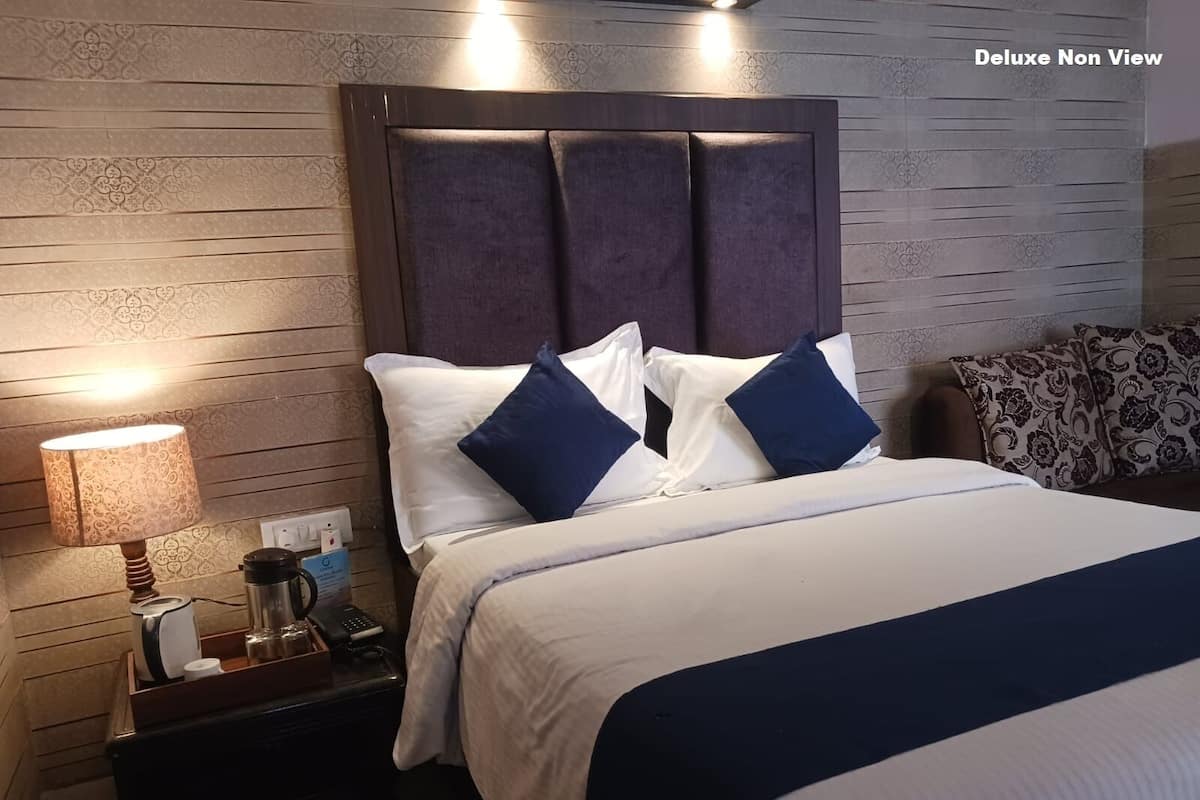 A hotel room with a large bed, a nightstand with a lamp, a phone, and a coffee maker.