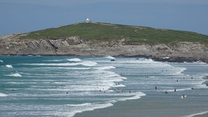 Une vue sur la côte, avec une colline et un phare.