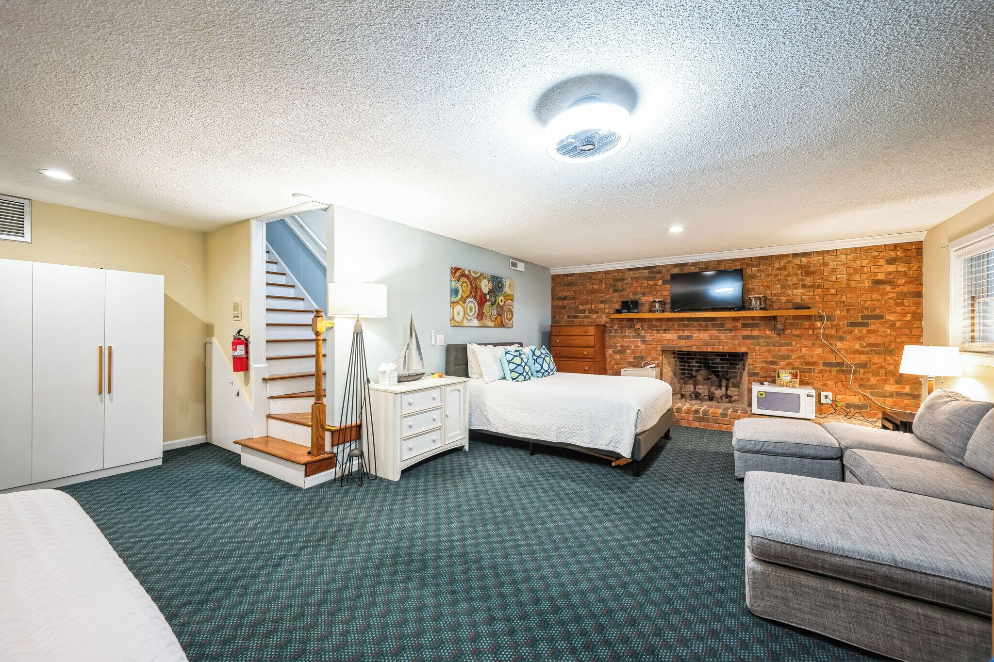 Une chambre d’hôtel avec un escalier, un lit, un canapé, une cheminée et un téléviseur.