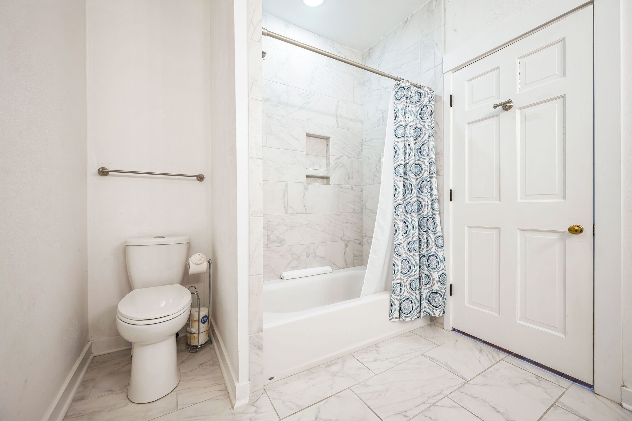 A bathroom with a toilet, a bathtub, and a shower curtain.