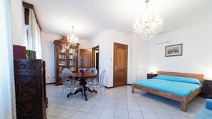 Un dormitorio con una cama de madera, una mesa de comedor con sillas, una araña y una estantería.