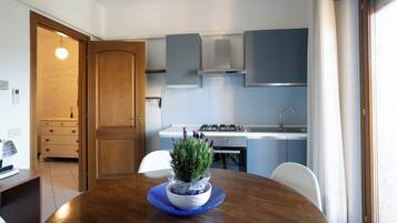 Una cocina compacta con área de comedor, que incluye una mesa de madera, una planta en maceta y un plato de vidrio azul.