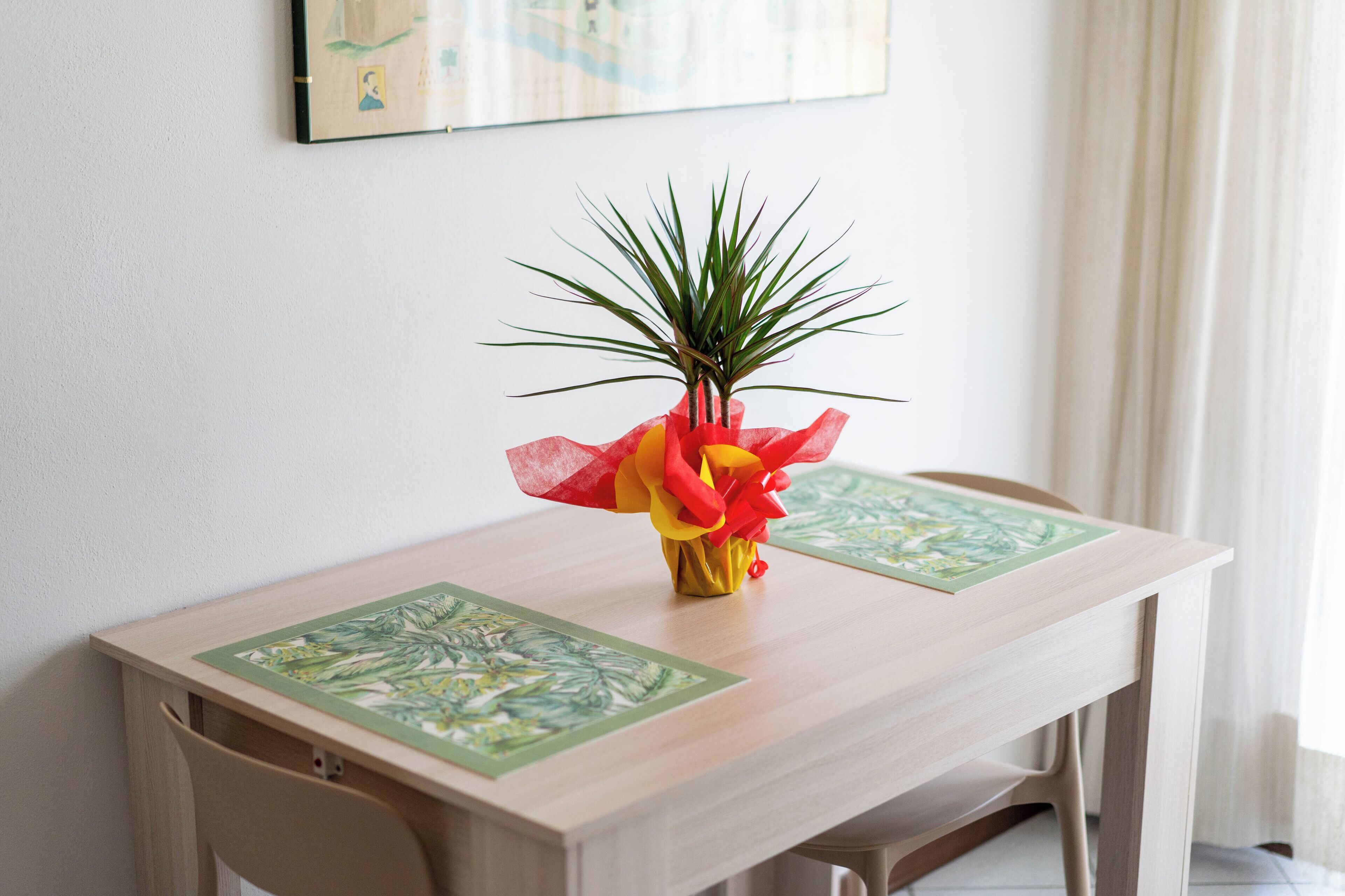 Une table de salle à manger en bois, avec une petite plante en pot placée au centre.