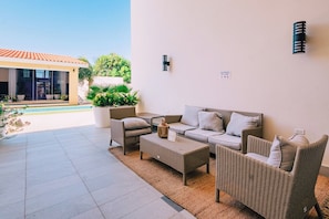 An outdoor seating area with wicker furniture, a small table, and a potted plant. - Elegant 2BR Condo with Pool Access in Noord, Aruba (Noord)