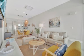 A modern living room with a sofa, chairs, a coffee table, and a dining area with a table and chairs. - Elegant 2BR Condo with Pool Access in Noord, Aruba (Noord)