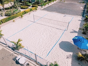 A beach volleyball court with a net, surrounded by sand and palm trees. - Elegant 2BR Condo with Pool Access in Noord, Aruba (Noord)