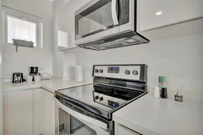 Una cocina moderna con microondas, horno y cafetera integrados.