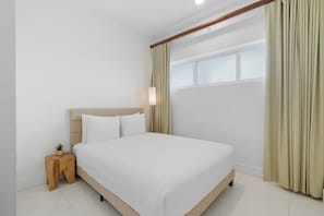 Une chambre à coucher avec un lit, une table de chevet, une fenêtre avec des rideaux et un luminaire fixé au mur.