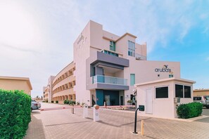 A modern hotel with a flat facade, multiple balconies, and a clear sky. - Modern Caribbean 2BR Condo with Pool Access, Noord (Noord)