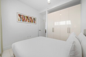 A bedroom with a bed, a wardrobe, and a framed artwork on the wall.