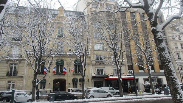 Un edificio histórico de estilo arquitectónico clásico, que destaca por su imponente entrada y múltiples banderas.