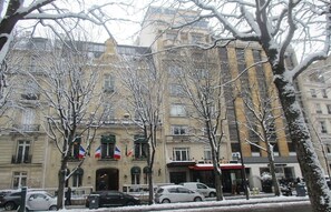 Un bâtiment historique doté d’un style architectural classique, caractérisé par une entrée imposante et la présence de plusieurs drapeaux.