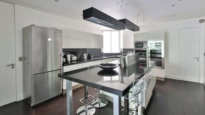 Una cocina moderna con electrodomésticos de acero inoxidable, una isla central con taburetes y un diseño elegante.