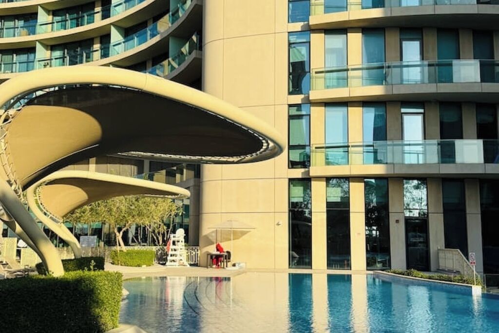 Een modern hotel met een golvend architectuur, een zwembad en een verzorgde tuin.