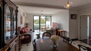 Una sala de estar amplia con un gran ventanal, un comedor con mesa de madera y una zona de estar acogedora con sofá.
