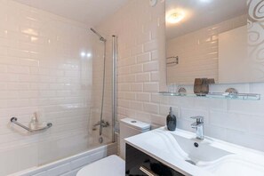 A bathroom with white subway tiles, a glass shower enclosure, a white sink with a modern faucet, and a glass shelf above the sink. - GuestReady - Beautiful sea view in Funchal (Funchal)