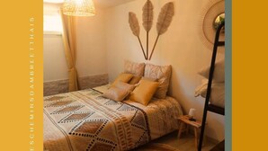 Une chambre à coucher avec une couvre-lit à motifs, un luminaire suspendu et des œuvres d’art murales.