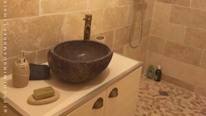 A bathroom with a round mirror, a vessel sink, a handheld showerhead, and a tiled floor. - Les Chemins d'Ambre & Thaïs: Charming dwelling in the heart of the Nantes vineyards (La Regrippière)