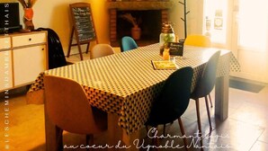 Un coin repas avec une nappe à carreaux, une cheminée et un tableau affichant le menu.