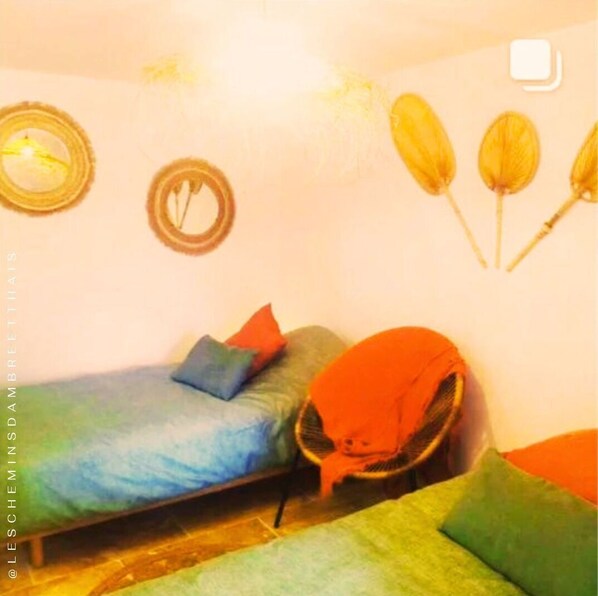A bedroom with a bed, pillows, a chair, and wall decorations. - Les Chemins d'Ambre & Thaïs: Charming dwelling in the heart of the Nantes vineyards (La Regrippière)
