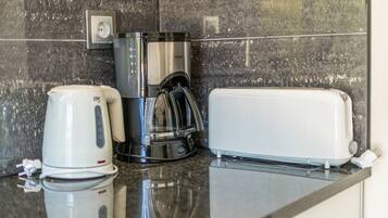A kitchen with a coffee maker, toaster, and a wall socket.