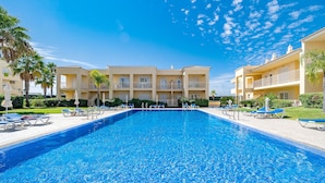 A swimming pool with lounge chairs and a building with balconies in the background. - Albufeira Palm Tree With Pool by Homing (Albufeira)