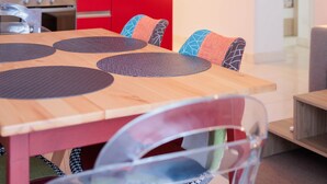 A modern kitchen with red cabinetry and a dining area with a wooden table and chairs.