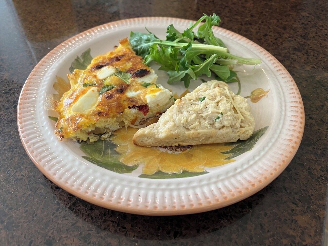 Un plato con una porción de quiche, un trozo de pastel y una ensalada acompañante sobre un plato de cerámica.