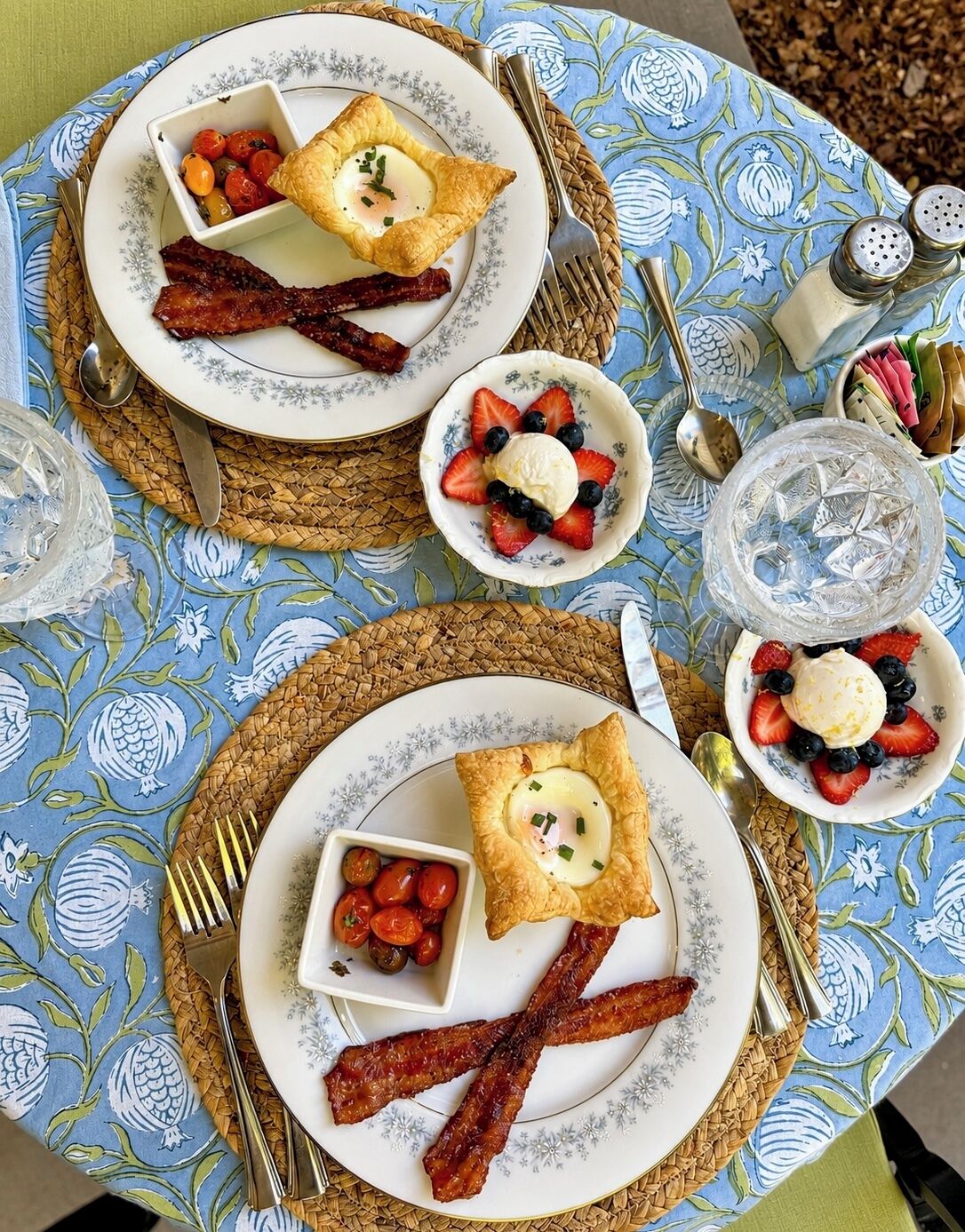 A breakfast setting with plates of food, including eggs, bacon, and fruit.
