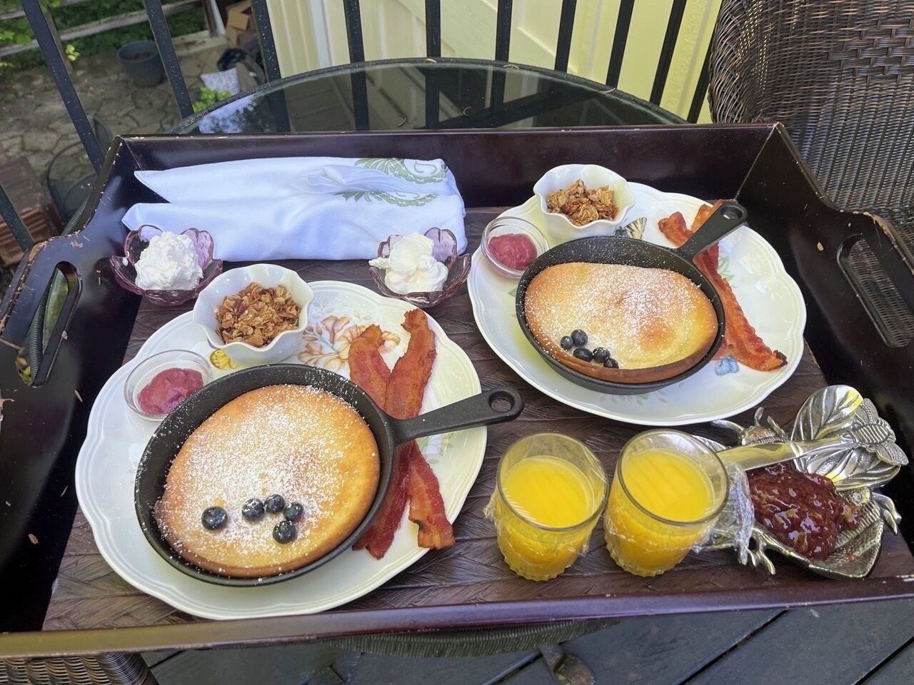 Ein Tablett mit Pfannkuchen, Speck, Blaubeeren und Beilagen auf einem Tisch.