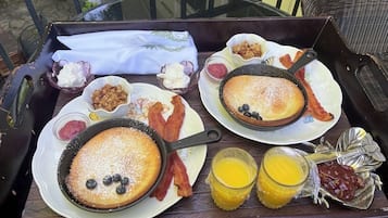 Ein Tablett mit Pfannkuchen, Speck, Blaubeeren und Beilagen auf einem Tisch.