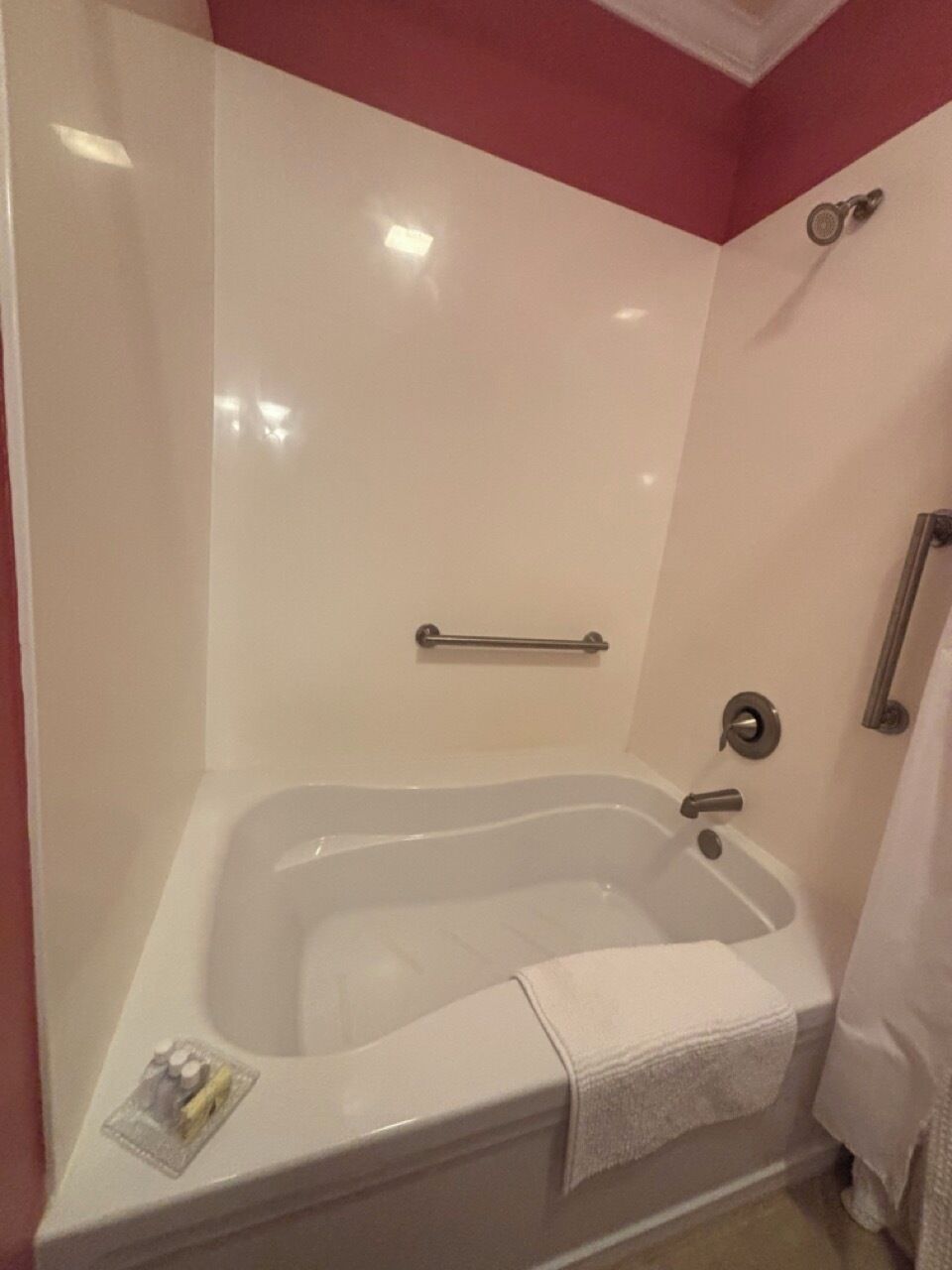Un baño con una bañera blanca, un asidero y una toalla.