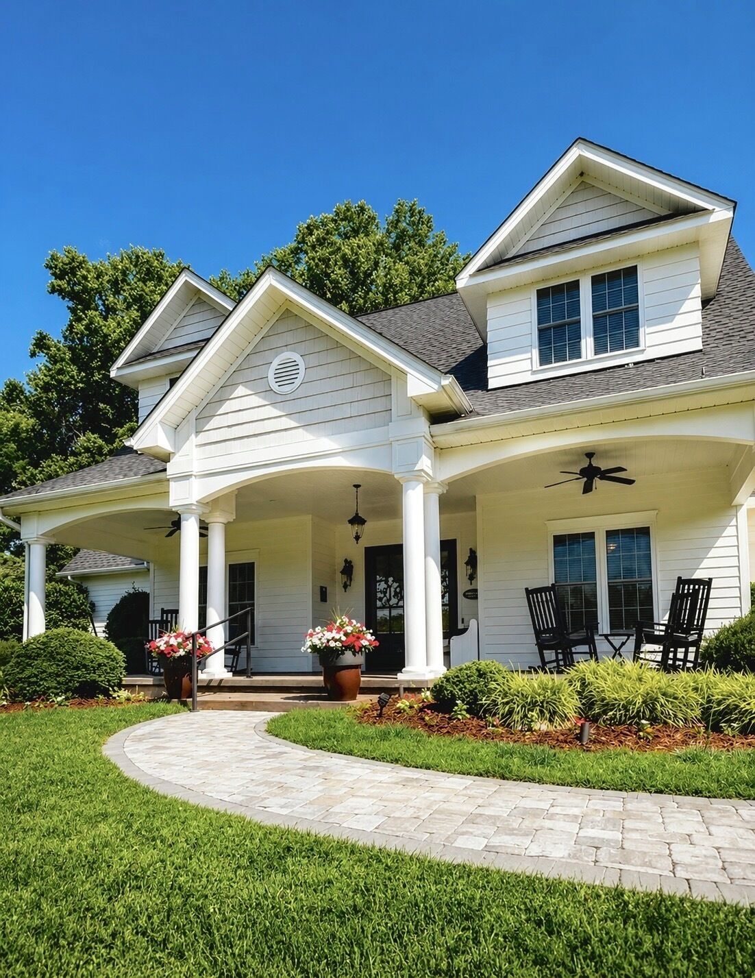 A two-story house with a covered porch, a front entrance, and a landscaped garden.