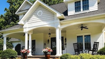 A two-story house with a covered porch, a front entrance, and a landscaped garden.
