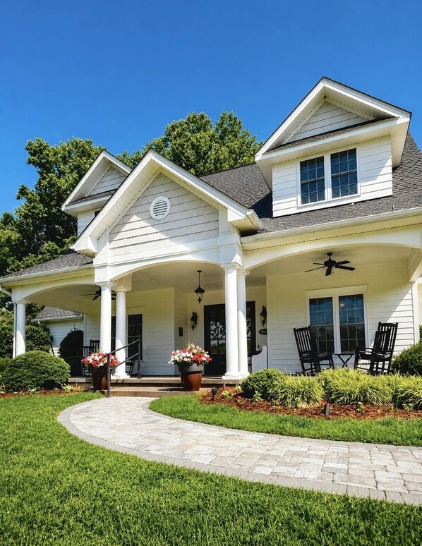 A two-story house with a covered porch, a front entrance, and a landscaped garden.