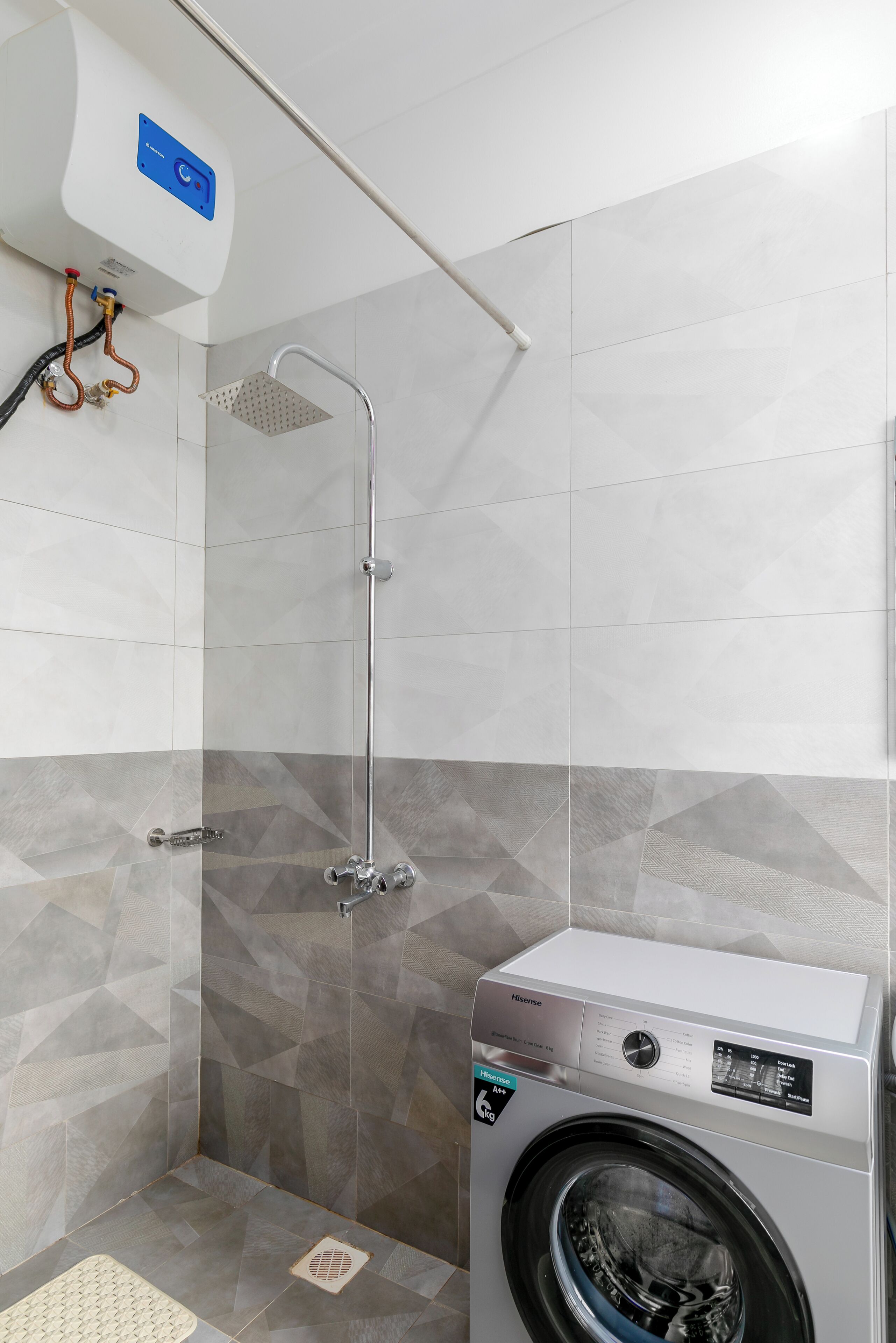 A modern bathroom with a built-in shower, a washing machine, and a tiled floor.