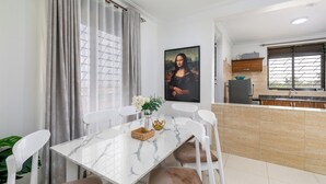 A dining area with a marble table, white chairs, and a painting of the Mona Lisa. - Elegant Apartment with Stunning Nature views. (Kampala)
