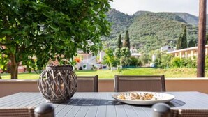 A table set outdoors with a plate of food, a decorative vase, and a view of a mountainous landscape.