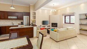 A modern living room with a sofa, a TV, and a dining area with a table and chairs.