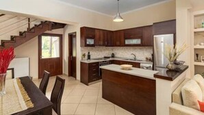 A modern kitchen with dark wooden cabinets, a central island, and a dining area with a table and chairs.