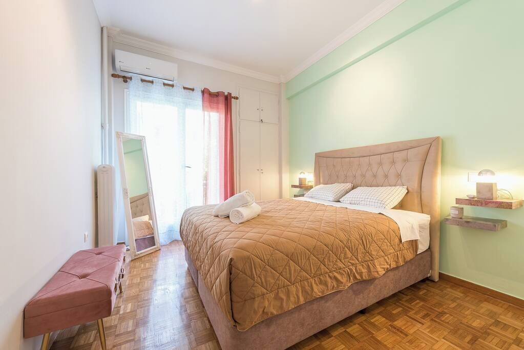 Une chambre à coucher avec un grand lit, un banc, un miroir et une armoire.