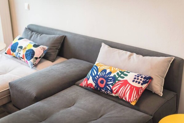 Un sofá gris con almohadones coloridos y estampados.