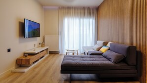 Una sala de estar moderna con un televisor de pantalla plana montado en la pared, un sofá, una mesita y un mueble de madera.