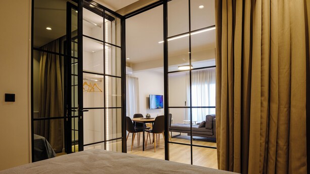 Una habitación de hotel con una cama, una mesa de comedor con sillas, un televisor y un sofá.