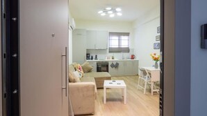 A compact living space with a kitchenette, a sofa, a dining table, and a small kitchen area. - Panathenaic Stadium Apartment by Greece Apartments (Athens)