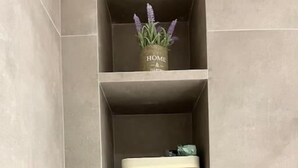 A shelf with a small plant, a wooden box, and rolled towels. - Panathenaic Stadium Apartment by Greece Apartments (Athens)