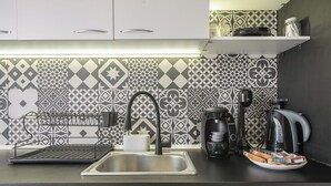 Eine moderne Küche mit Spüle aus Edelstahl, einer schwarzen Bosch-Kaffeemaschine und einem schwarzen Wasserkocher.