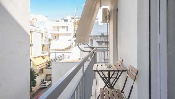 Ein Balkon mit einer Holzbank, einem Geländer und Blick auf die Stadt.