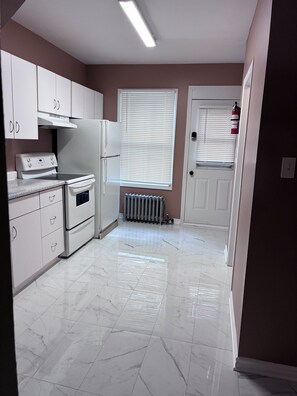 A kitchen with white cabinets, a stove, and a refrigerator. - Monthly rental - 1-BDR apt, ALL included (hot water, hydro and heating). (Ottawa)