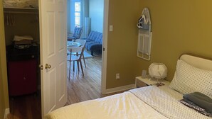 A bedroom with a bed, a chair, a desk, and a wardrobe. - Monthly rental - 1-BDR apt, ALL included (hot water, hydro and heating). (Ottawa)